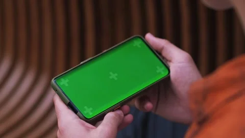 Hand man holding a smartphone touching phone with horizontal green screen phone Stock Footage 243374511