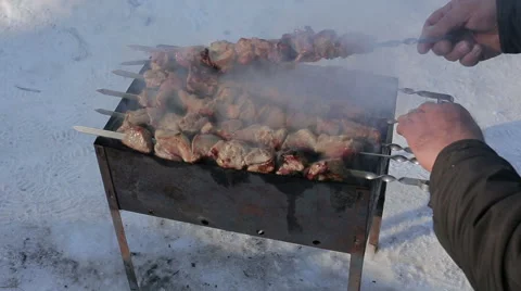 The hand of man inspects meat slices in sauce on fire Stock Footage 60437740
