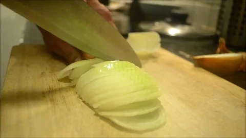Hand of a Man with a Knife Chopping an Onion in a Board Stock Footage 77949839