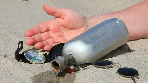Hand of a man lies next to a leaking water bottle in the sand Stock Footage 11140120