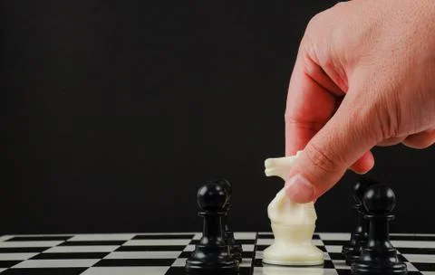 Hand man making move with white horse (knight) on chess board. Stock Photos