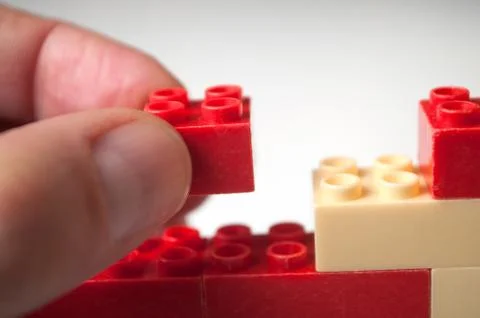 Hand of man playing with plastic bricks construction Stock Photos
