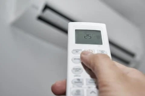 Hand of a man pressing the buttons on the control of a split air conditioner Stock Photos