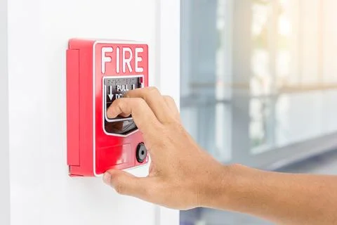 Hand of man pulling fire alarm switch on the white wall as background for e.. Stock Photos