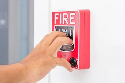 Hand of man pulling fire alarm switch on the white wall as background for e.. Stock Photos