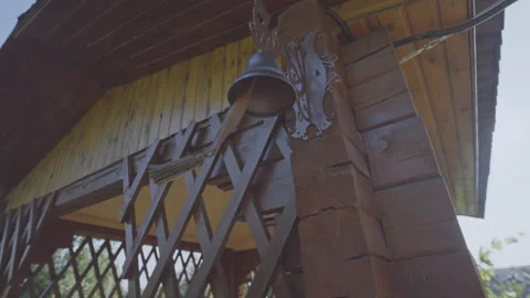 Hand of man pulls rope of copper bell hanging on arbor Stock Footage 256040230