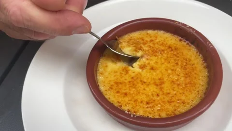 Hand of the man with a spoon taking a piece of Crema Catalana dessert Stock Footage 341430053
