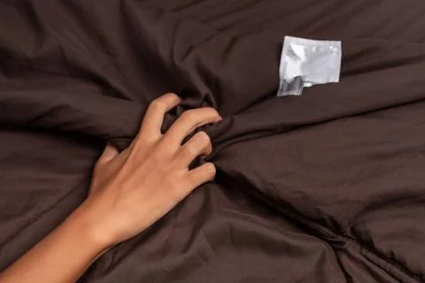 The hand of a man, Squeezing the bed sheet, from wild passion, next to which Stock Photos