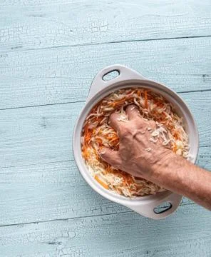 Hand of man squeezing grated cabbage and carrot Stock Photos