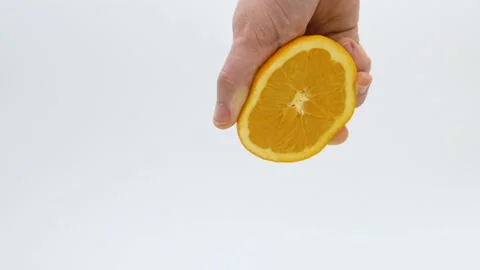 Hand of a man squeezing the juice from a half of an orange in slow motion Stock Footage