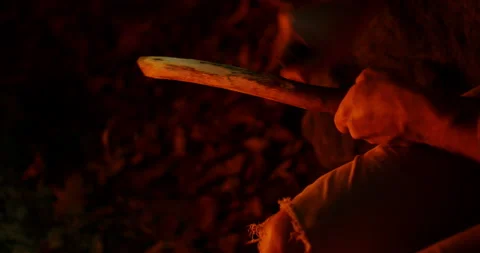 Hand of a man stoking a burning campfire with a stick Stock Footage 152851536