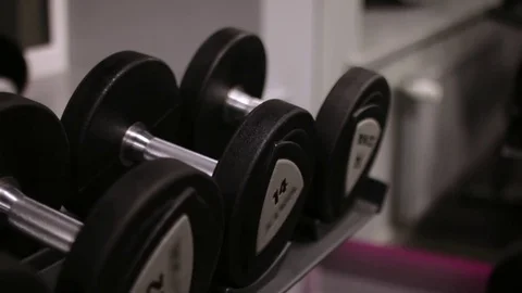 Hand of a man taking a dumbbell out of set of black weights Stock Footage 83129256