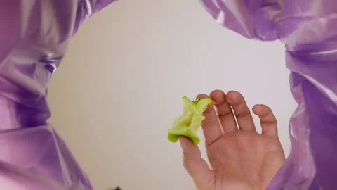 The hand of a man throwing an apple core into a garbage bag. View from inside Stock Footage 165108903