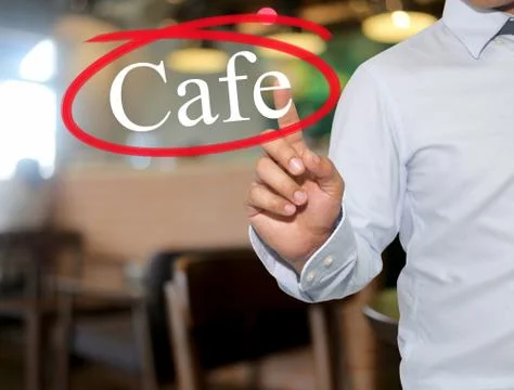 Hand of man touching text Cafe with white color on blur interior background. Stock Photos