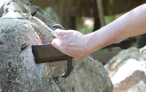 Hand of a man trying to pull the legendary Excalibur sword from Fotos Stock