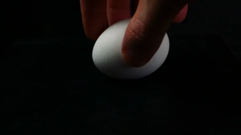 Hand of a man turns a chicken egg on a table Video stock 87216356