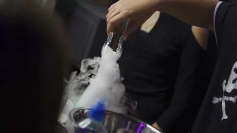 Hand of man uses forceps and puts ice cube into a flask with smoke, indoor Stock Footage 161990654