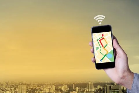 Hand of man using map on smartphone application with cityscape background. Stock Photos