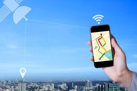 Hand of man using map on smartphone application with cityscape background. Stock Photos