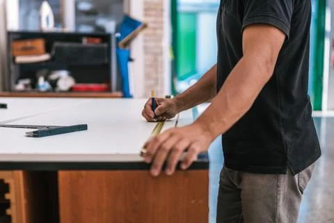 Hand of a man using a pencil to mark a measured point on a surface in a workshop Stock Photos