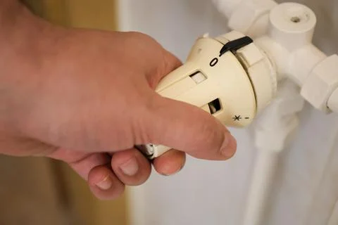 Hand of a man using a thermostat to adjust the temperature Stock Photos