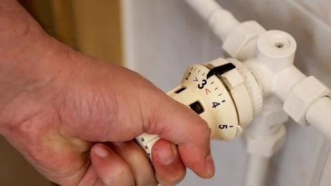 Hand of a man using a thermostat to adjust the temperature Fotos de archivo