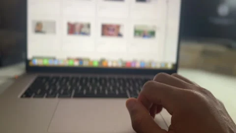 Hand of a man viewing a website on a laptop and browsing thumbnails Video stock 336183196