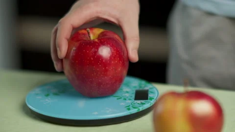 Hand of a man weighs several red apples on a kitchen scale, close-up Stock Footage 132043631