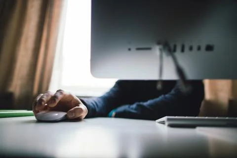 Hand of a man working at computer. Hand on the computer mouse. The monitor's in Stock Photos