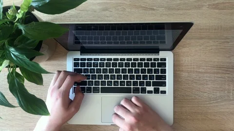 Hand of a man working at laptop computer typing on a keyboard on dark desktop. Stock Footage 107612066