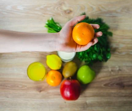 In the hand of the Mandarin on a background of vegetables Stock Photos