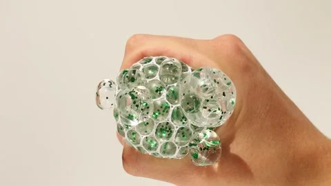 Hand manipulating crystal clear stress ball with green hydrogel bubbles Video stock 311012545