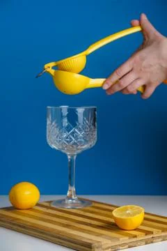Hand with Manual hand lemon squeeser making lemonade in a coctail glass with  Stock Photos