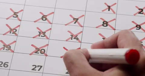 Hand Marking Calendar Dates with Red Pen for Countdown or Schedule Stock Footage 323995937