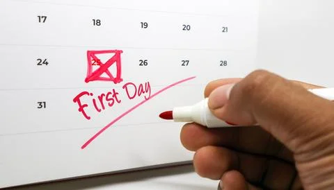 A hand marking First Day and crossing out the 25th on a calendar with a red.. Stock Photos