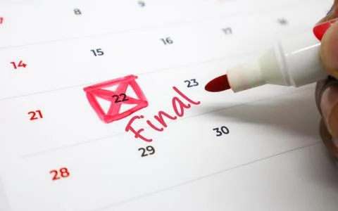 Hand marking an important final deadline on a white calendar with a red mar.. Stock Photos