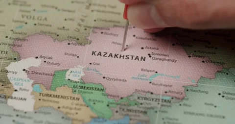 Hand marking Kazakhstan on a world map with a red flag pin Stock Footage 345589321