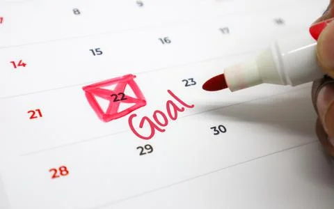 A hand marks a date on a calendar with a red marker, indicating a significa.. Stock Photos