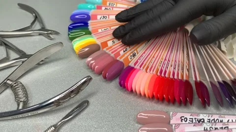 Hand of the master in black disposable glove goes through samples nail polish Video stock 144497491