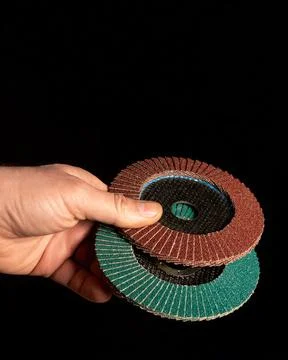 Hand of the master hold two Flap Discs close up on black background Stock Photos