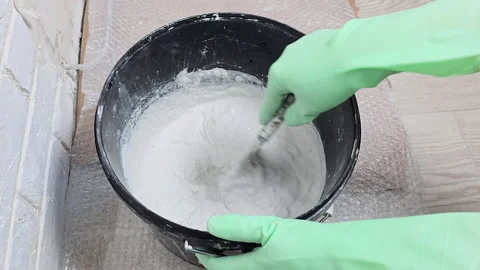 The hand of the master stir the plaster in a bucket with a spatula Stock Footage 237259305