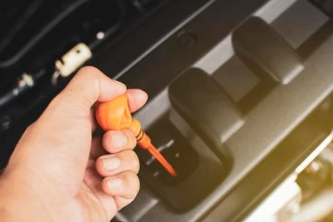 Hand of mechanic has pull yellow dipstick for checking engine oil level. Foto stock