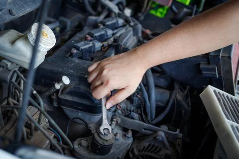 Hand of mechanic using a silver combination wrench to work on a pulley bolt Stock Photos