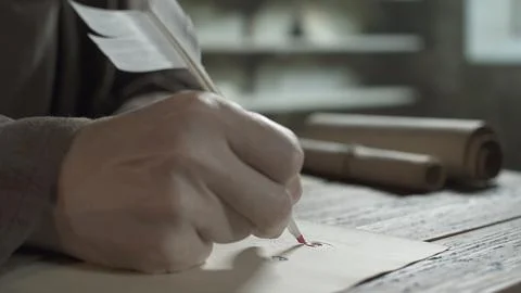 Hand of medieval scribe decorating initial calligraphic letter with quill pen Stock Photos