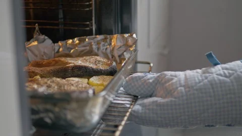 Hand In A Mitten Pulls Out Of Oven A Dish Of Baked Potatoes And Steaks Salmon Stock Footage 116885560