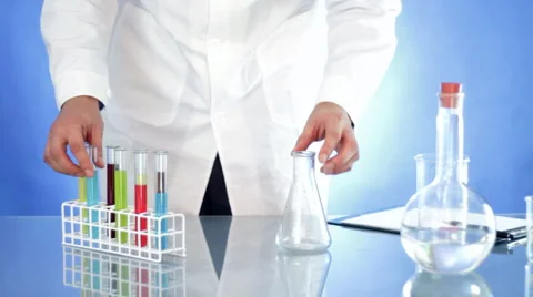 Hand mixing chemicals from test tubes into Erlenmeyer flask in research lab Stock Footage
