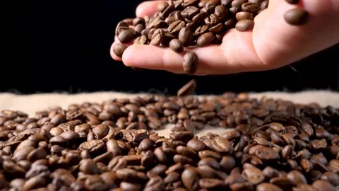 Hand mixing roasted coffee beans. Slow motion of arabica coffee seeds. Video stock 154207984