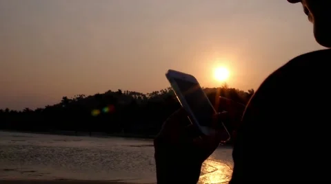 Hand with Mobile Phone against Sunset on the Beach Vidéo 46731886