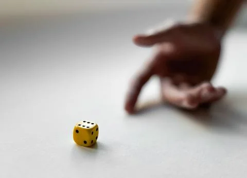 Hand in motion with yellow dice on a white surface capturing chance and luck Stock Photos