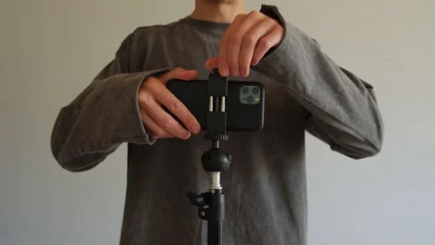 Hand mounting smartphone on tripod close up blogging content creation. Video stock 315117192